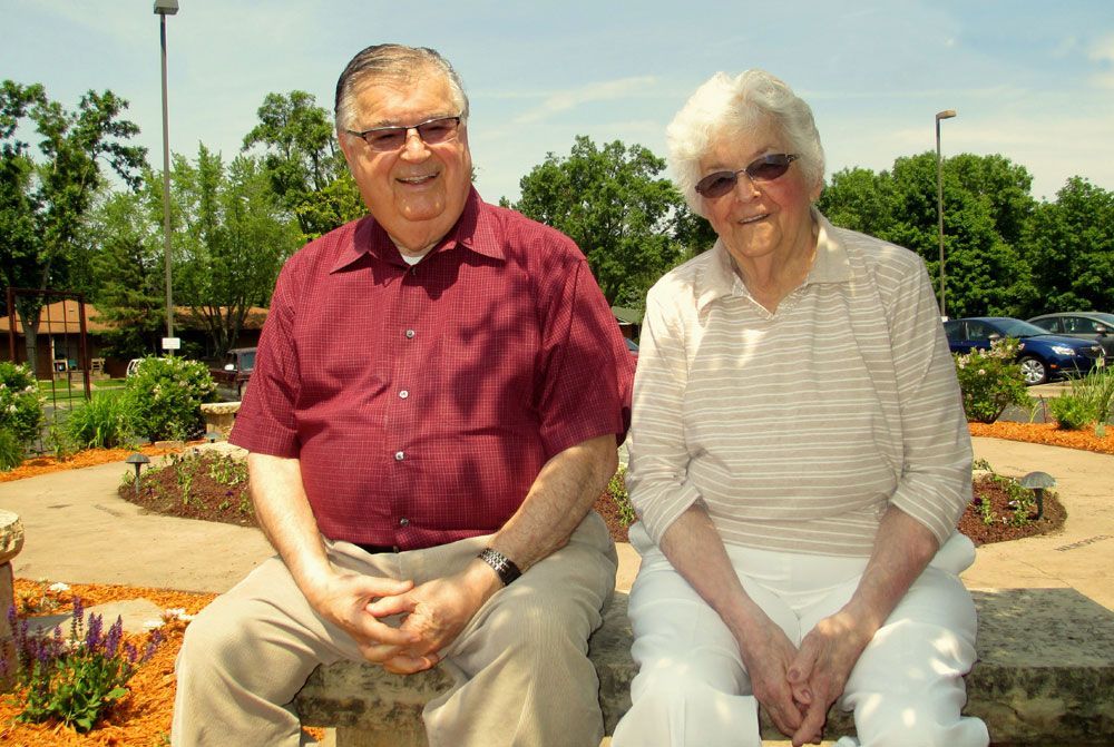 A man and a woman are sitting next to each other holding hands