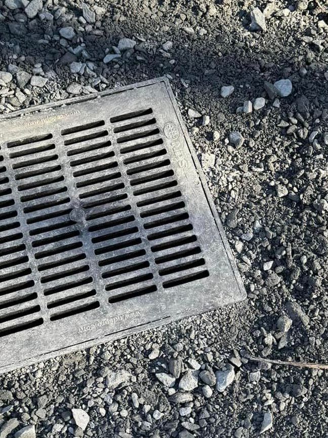 A manhole cover is sitting on the ground next to a pile of gravel.
