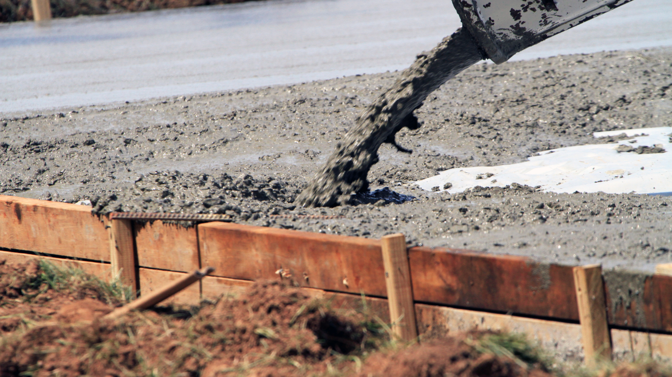 A person is pouring concrete into a hole in the ground.