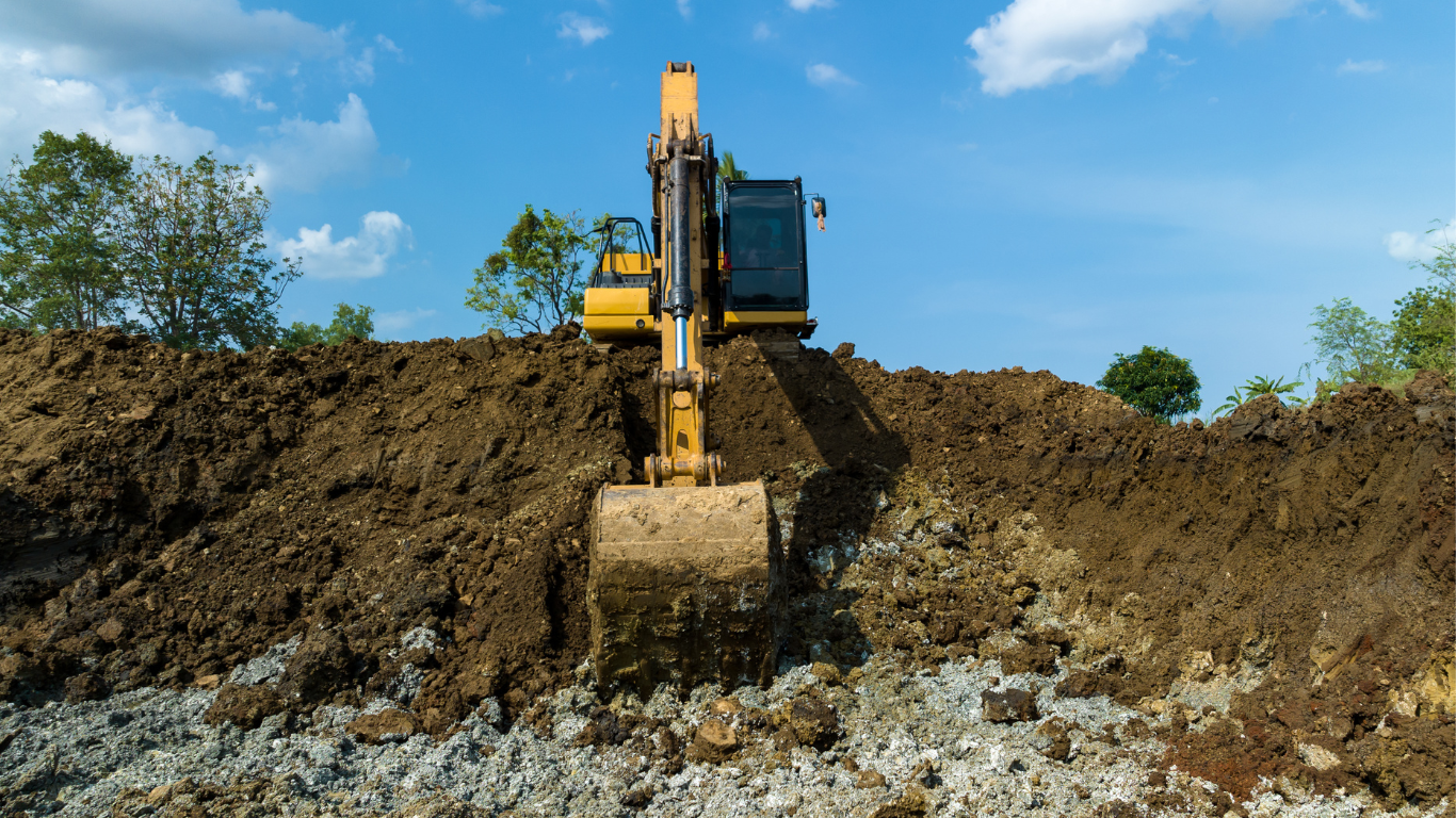 A yellow Tailored Excavation excavator is digging a hole in a pile of dirt.
