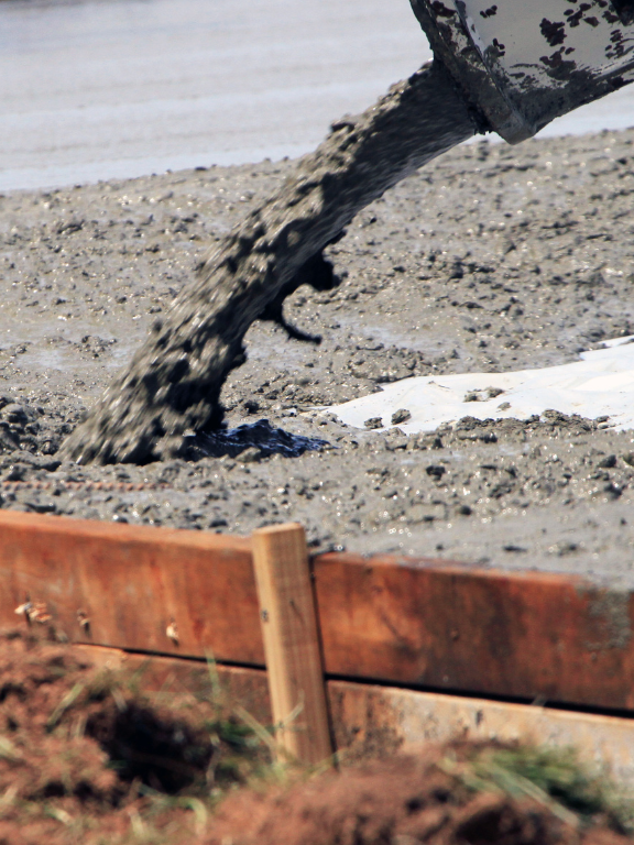 Tailored Excavation is pouring concrete into a wooden form.