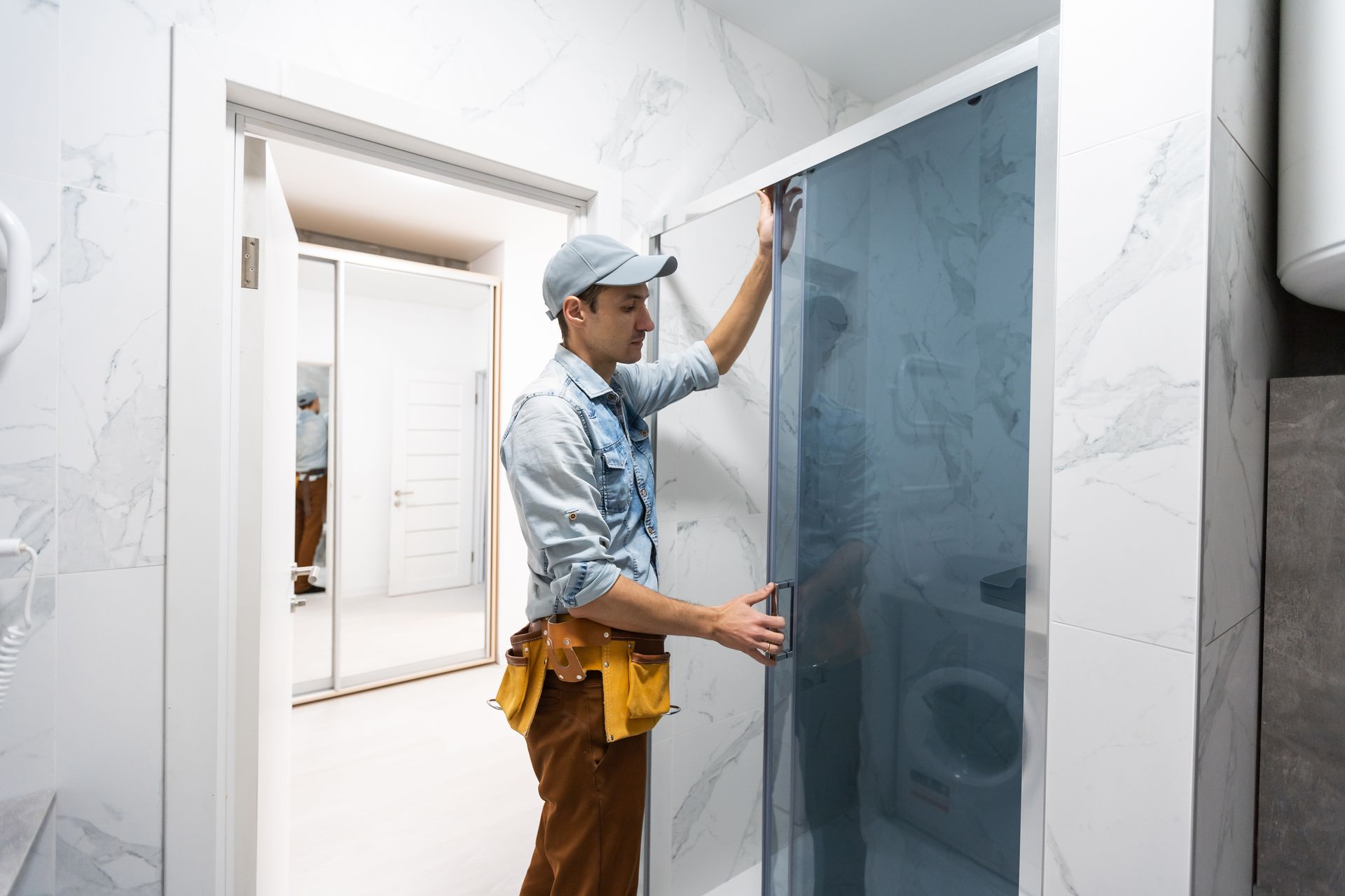 a man is installing a shower door in a bathroom .