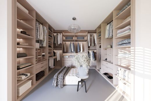 Bright walk-in closet with shelves, hanging clothes, and folded linens around a central island.