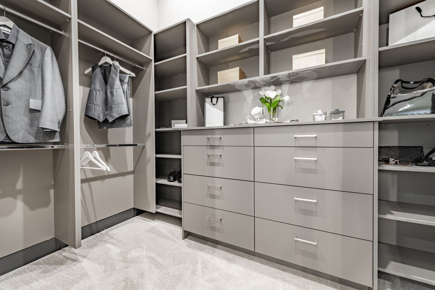 Walk-in closet with gray cabinets, hanging clothes, drawers, and shelves in a modern home