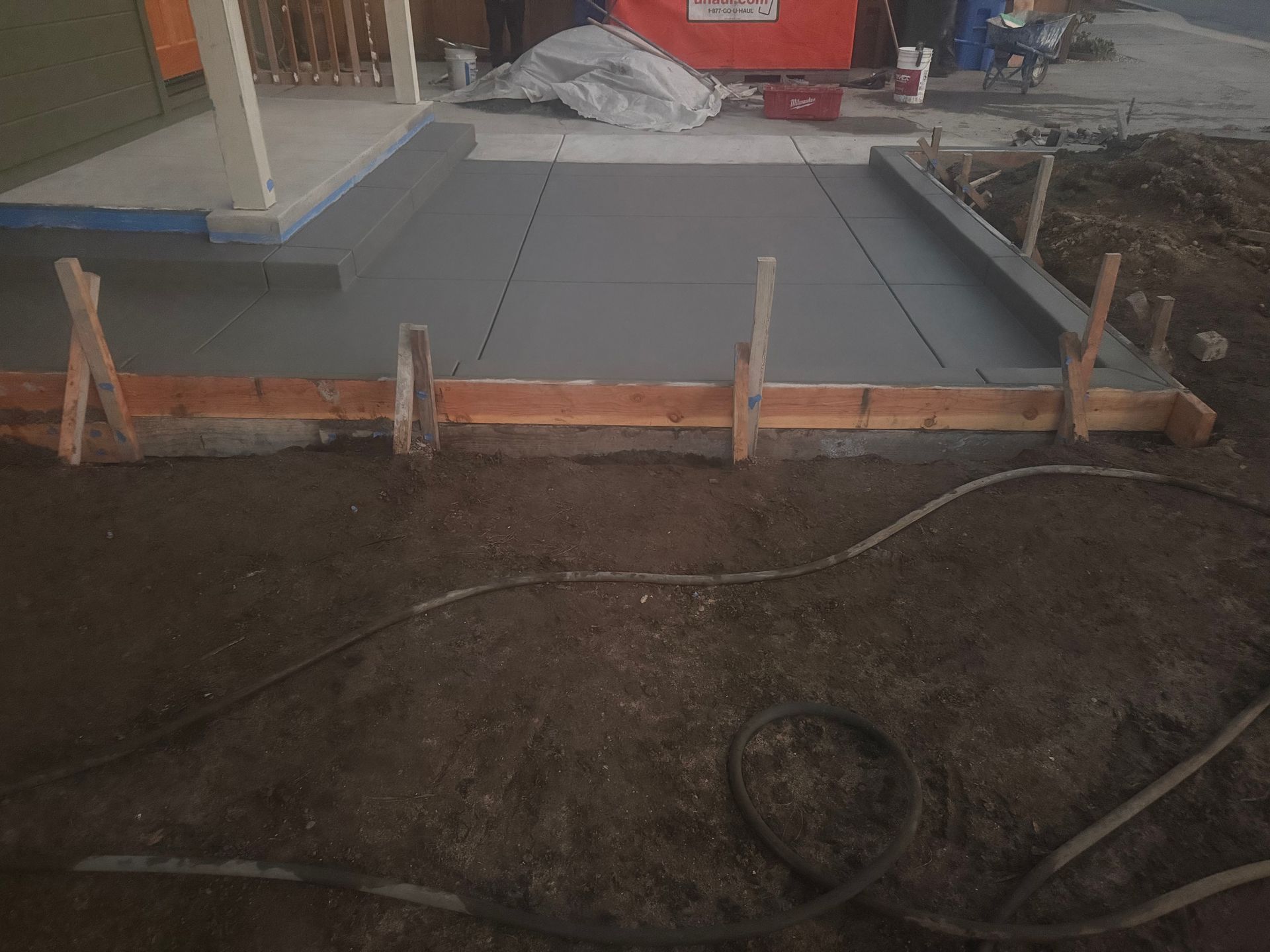 Freshly poured concrete walkway with wooden forms and stakes.