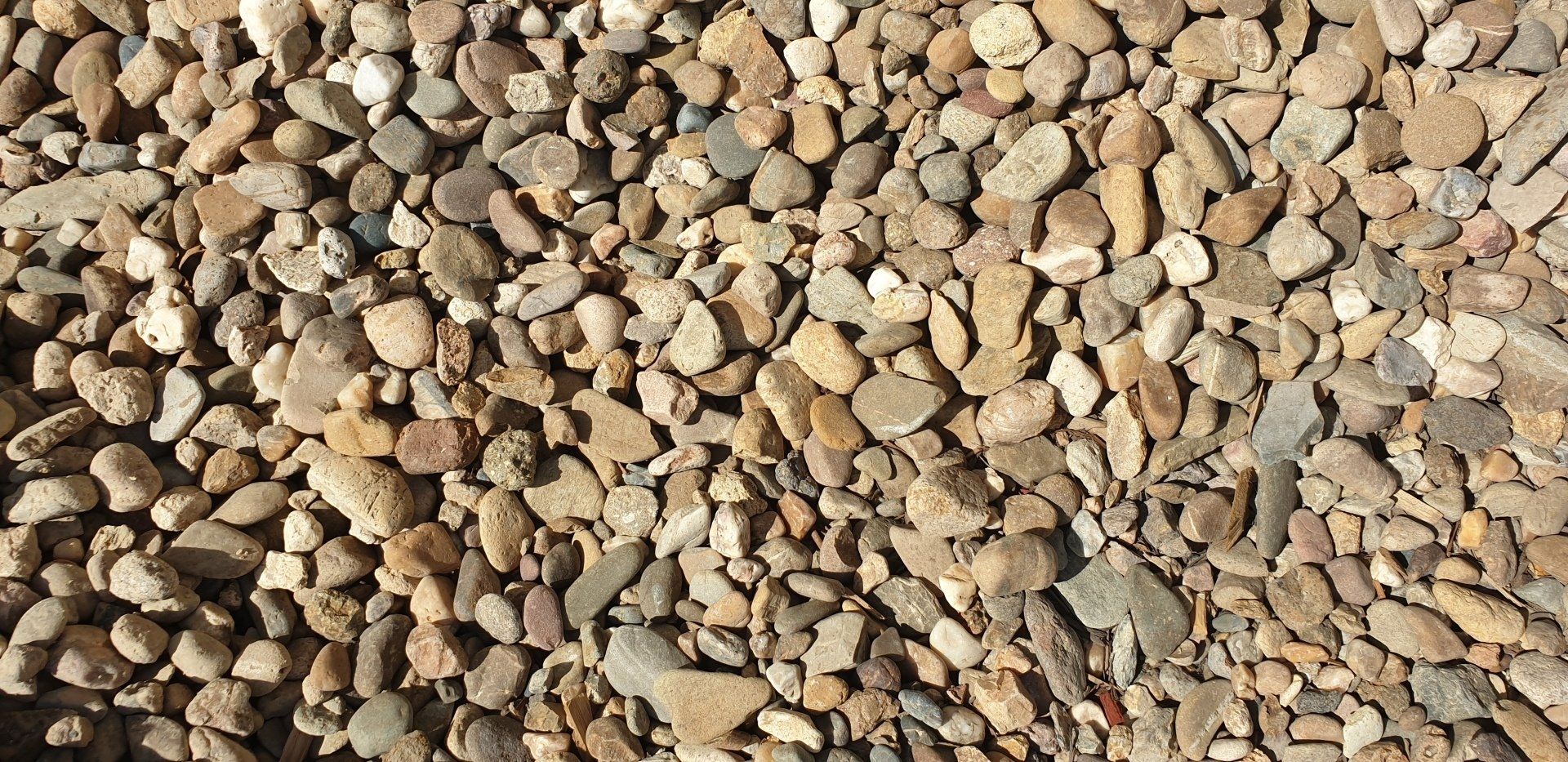 Close-up of a pile of small, light brown and gray pebbles.