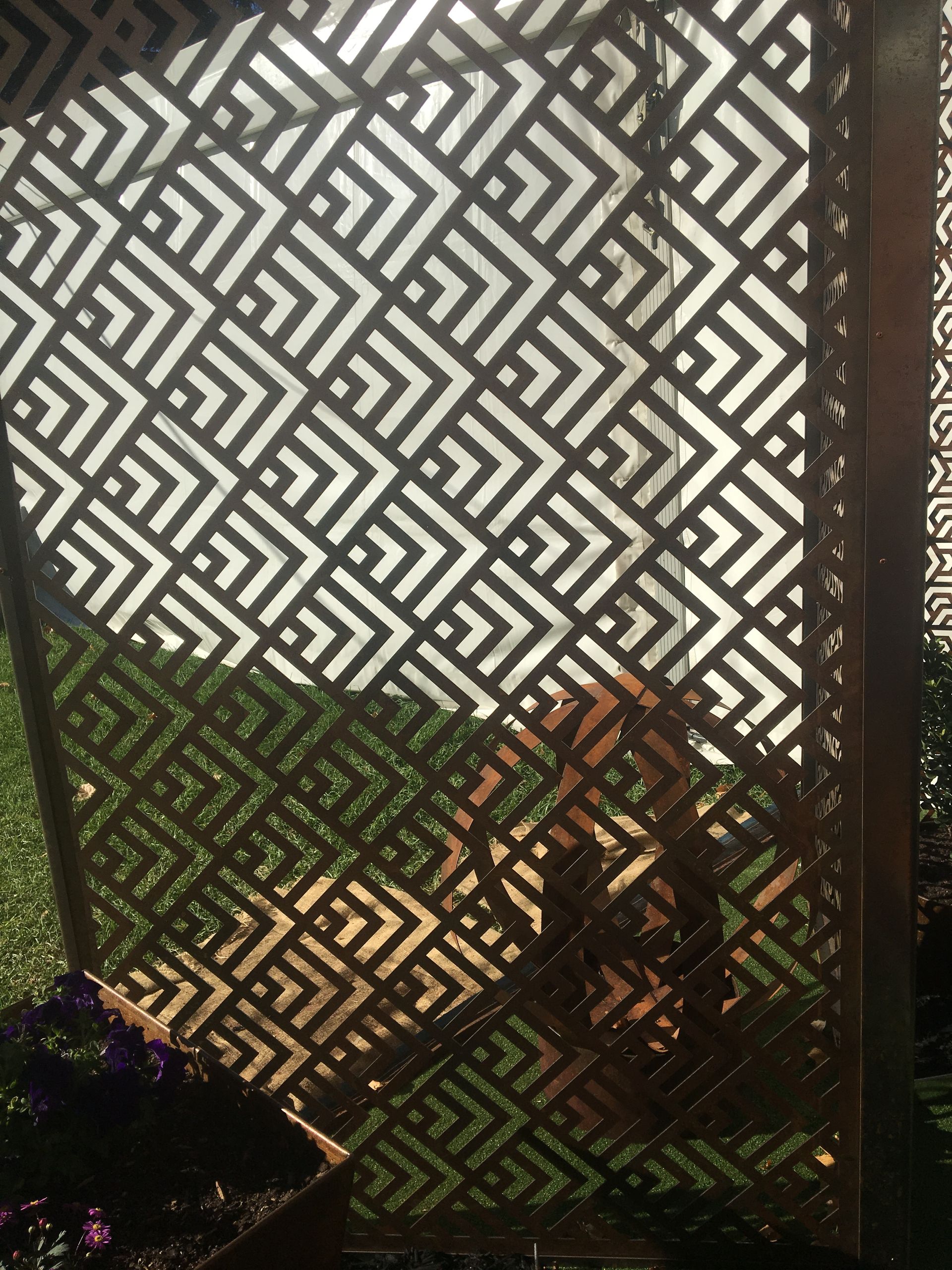 Geometric patterned screen with sunlight and blurred figure.