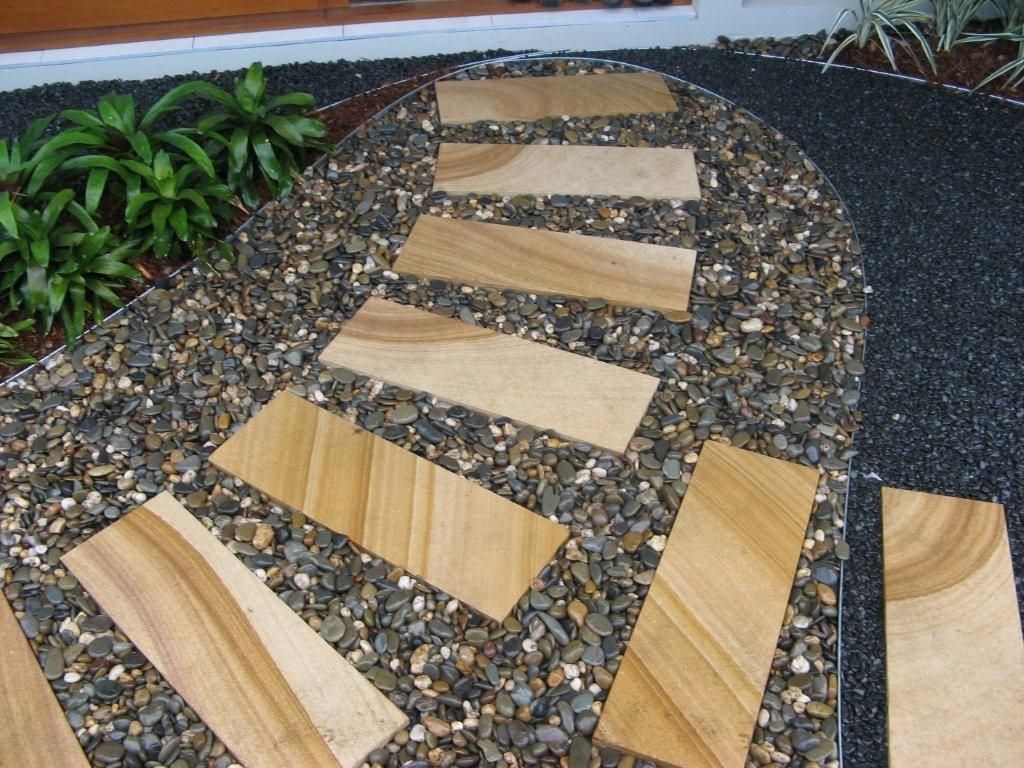 Pathway of rectangular stone steps through small gravel.