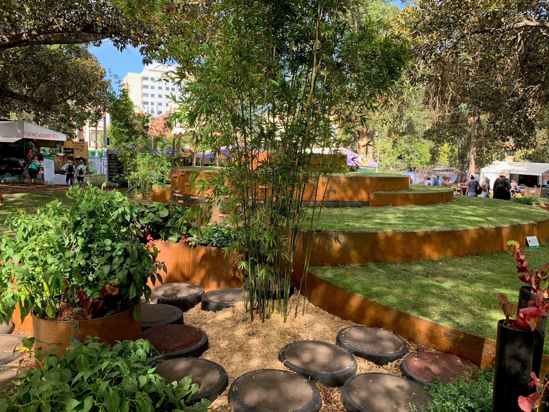 Outdoor garden with layered grass platforms, trees, and stepping stones.