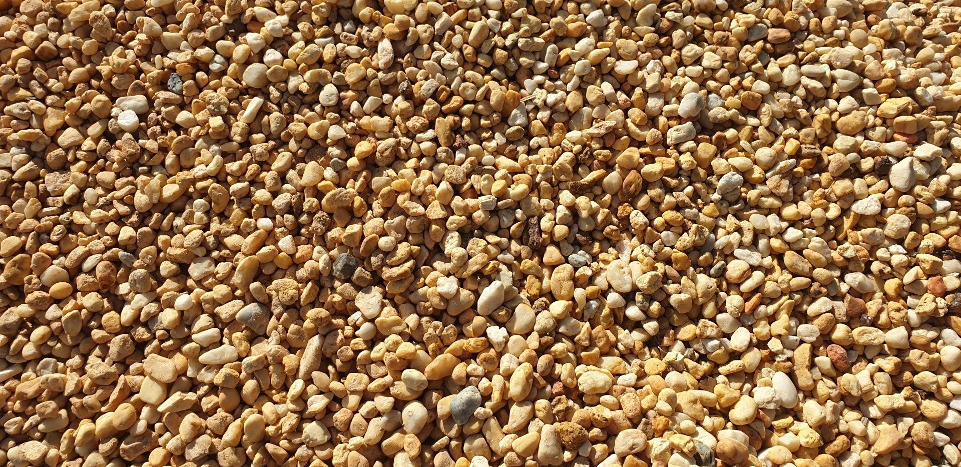 Close-up of a pile of small, smooth, beige and tan pebbles.