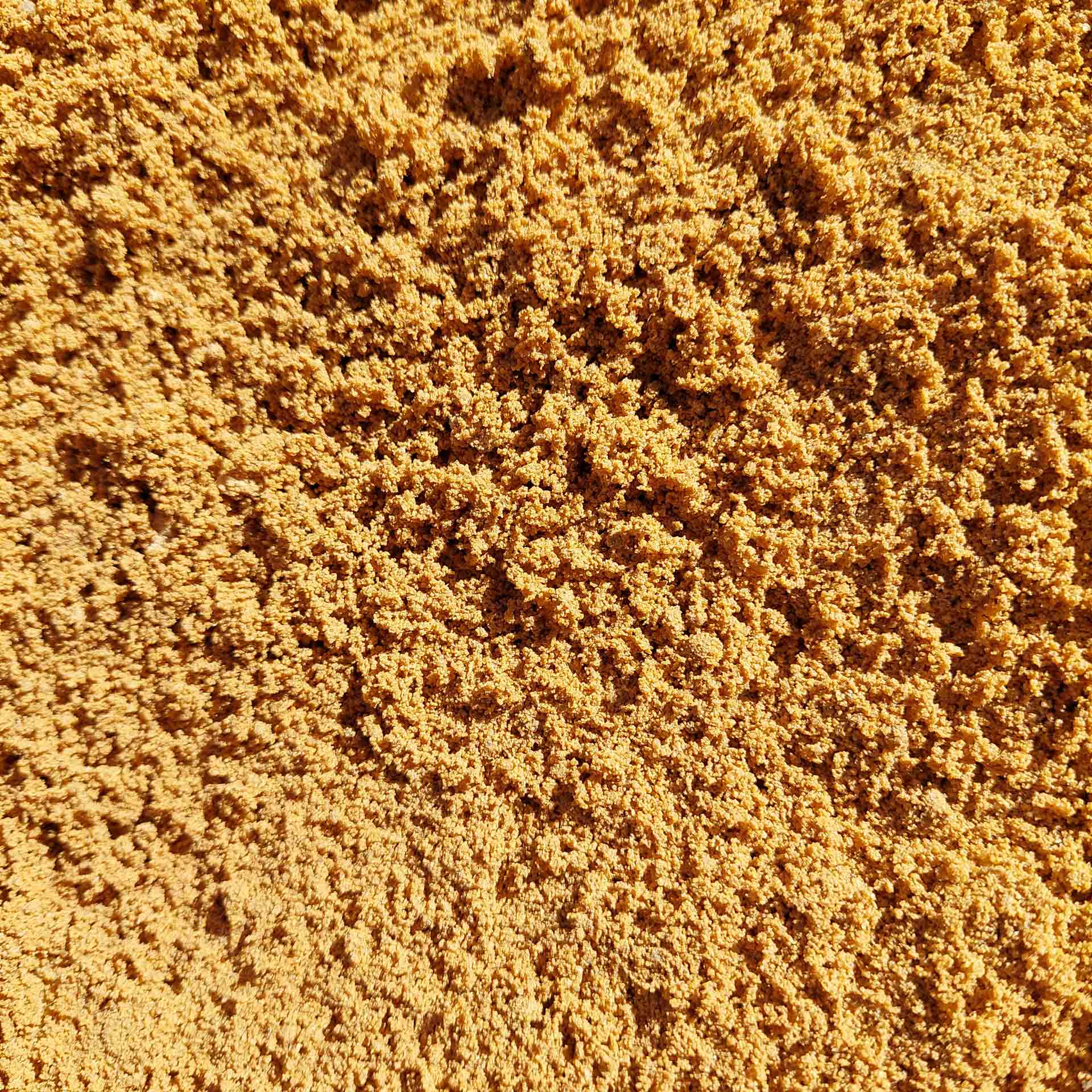 Close-up of tan-colored sand with a textured, uneven surface.