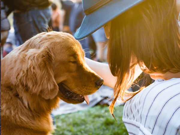 A woman in a hat is petting a dog.