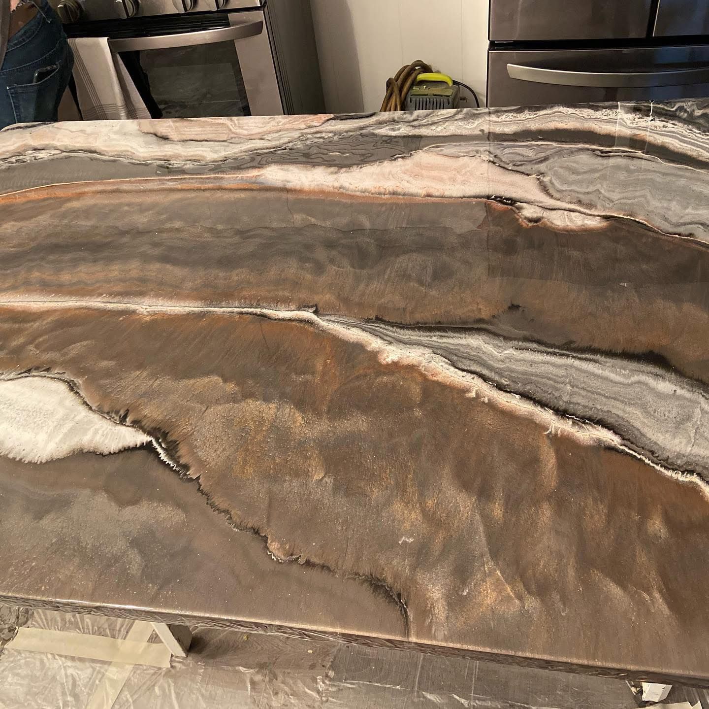 A close-up of a kitchen countertop with a polished, swirling stone pattern in shades of brown, gray, and white.