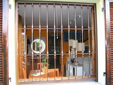 Sbarre di sicurezza in metallo che coprono la vetrina di un negozio con scaffali e uno specchio rotondo all'interno