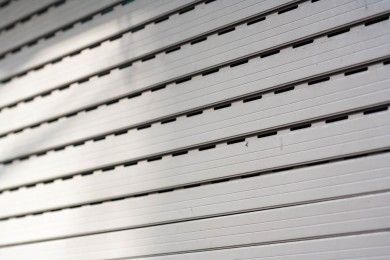 File diagonali di lamelle metalliche grigio chiaro con prese d'aria scure, che formano un motivo industriale astratto.