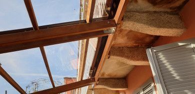 Lucernario con travi in legno e pannelli traslucidi sopra una stanza con tenda alla finestra