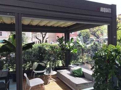 Patio coperto con moderni posti a sedere all'aperto, piante e vista su una strada della città.