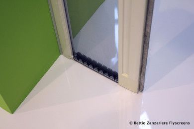 Angolo con porta a vetri con cornice beige e parete verde accanto a pavimento bianco