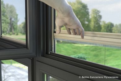 Una mano si protende verso una finestra aperta, con un giardino verde all'esterno.