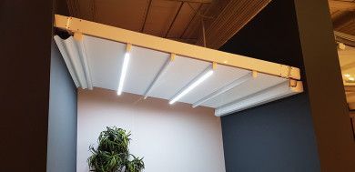 Soffitto o baldacchino a doghe bianche con strisce LED sopra una parete e una pianta in uno spazio interno
