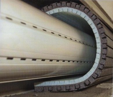 Primo piano di un grande tubo industriale che attraversa un'apertura circolare rivestita di mattoni.