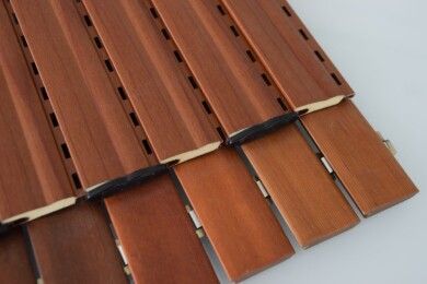 Listelli di legno marrone impilati su una superficie bianca, con distanziatori neri.