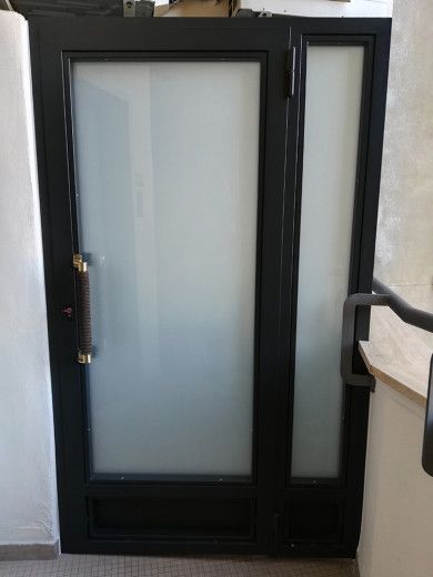 Porta in vetro satinato con cornice nera e pannello laterale stretto in un corridoio