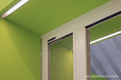 Angolo interno dipinto di verde con finestra incorniciata di bianco e tende trasparenti vicino al soffitto