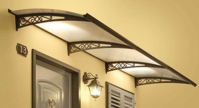 Tende da sole decorative in metallo sopra una porta e una finestra beige su una parete in stucco.