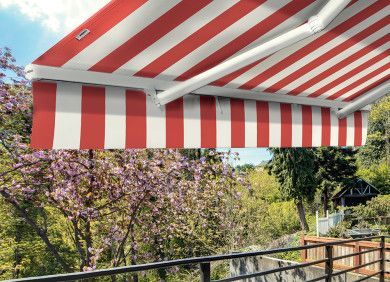 Tenda a strisce rosse e bianche su una vista di un giardino con alberi viola in fiore e una ringhiera in legno.