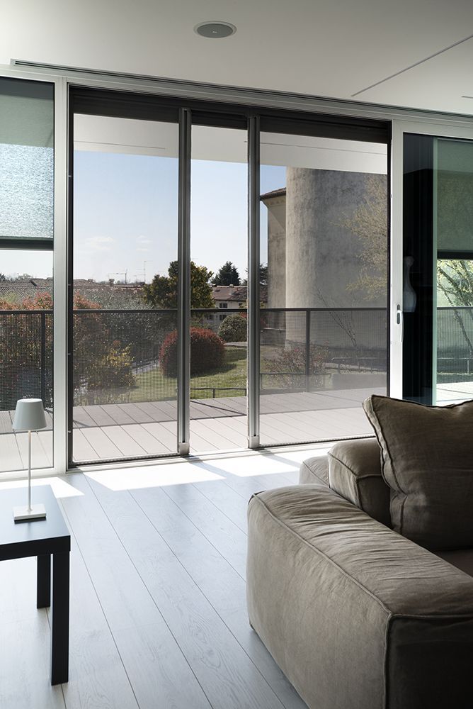 Soggiorno moderno con divano beige di fronte a grandi porte scorrevoli in vetro con vista sull'esterno.