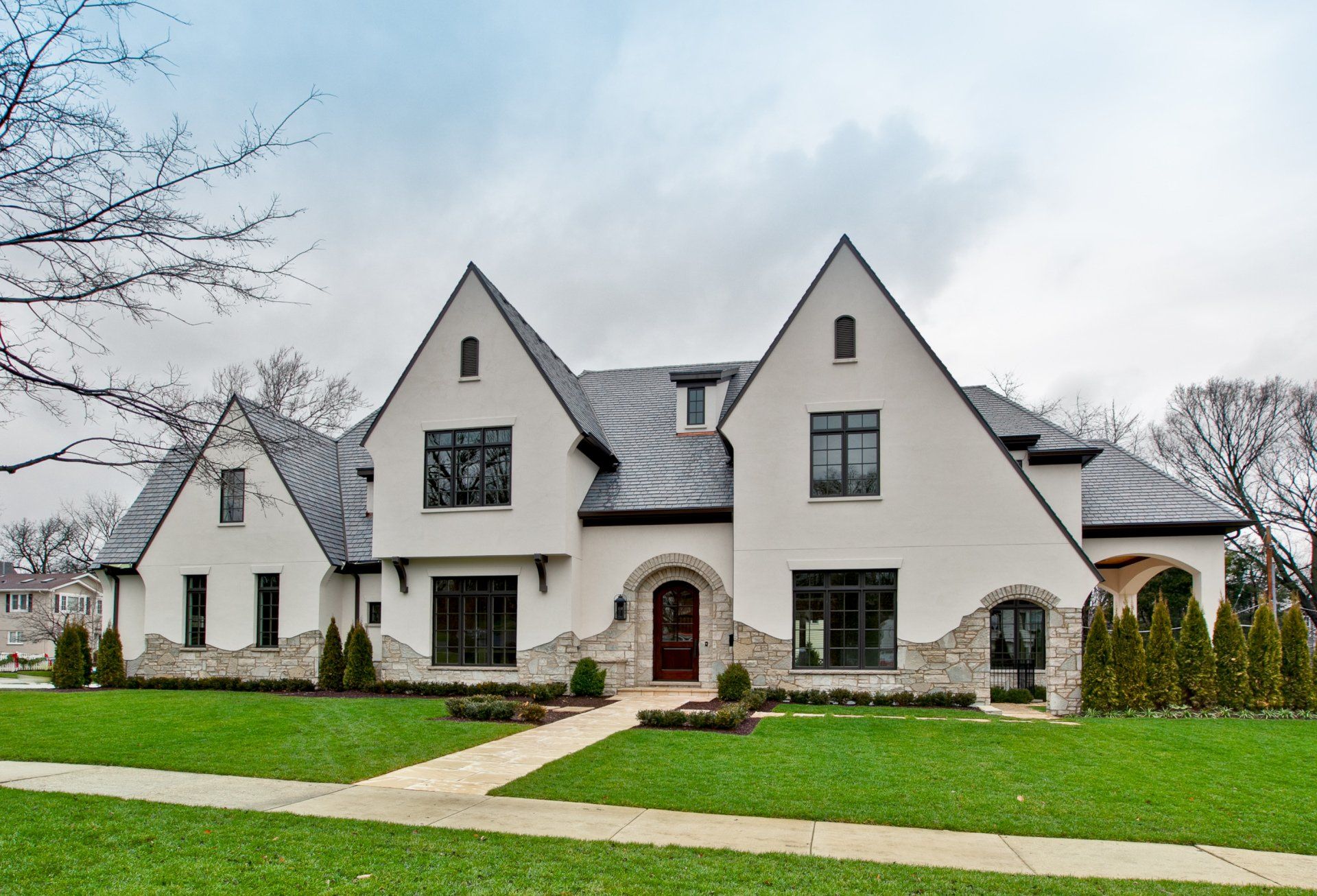 A large white house with a black roof is sitting on top of a lush green lawn.