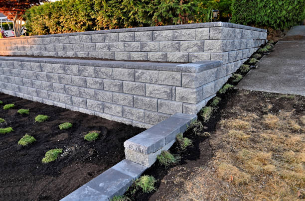 A brick wall is being built in a garden next to a sidewalk.