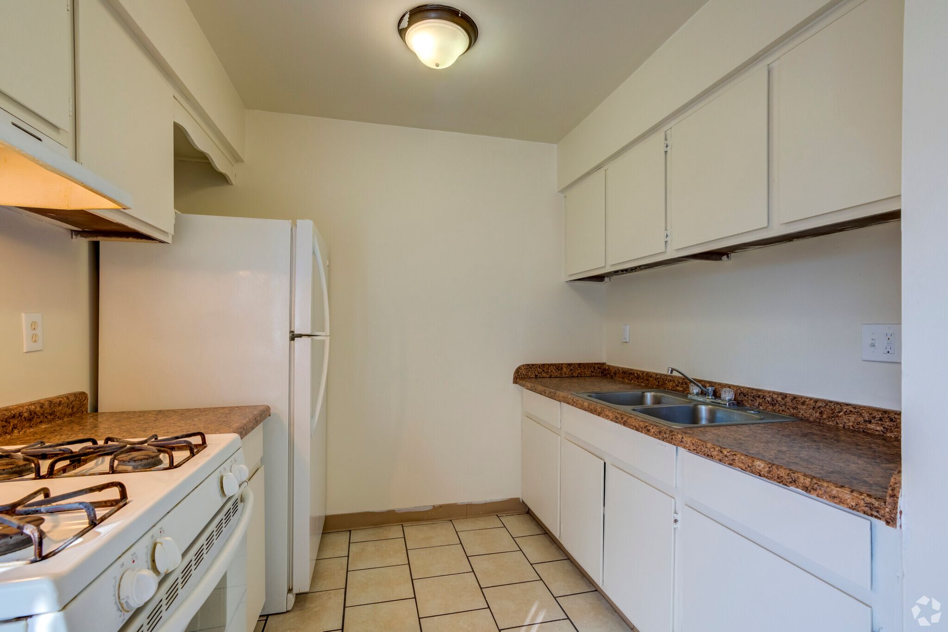A kitchen with a stove , refrigerator and sink