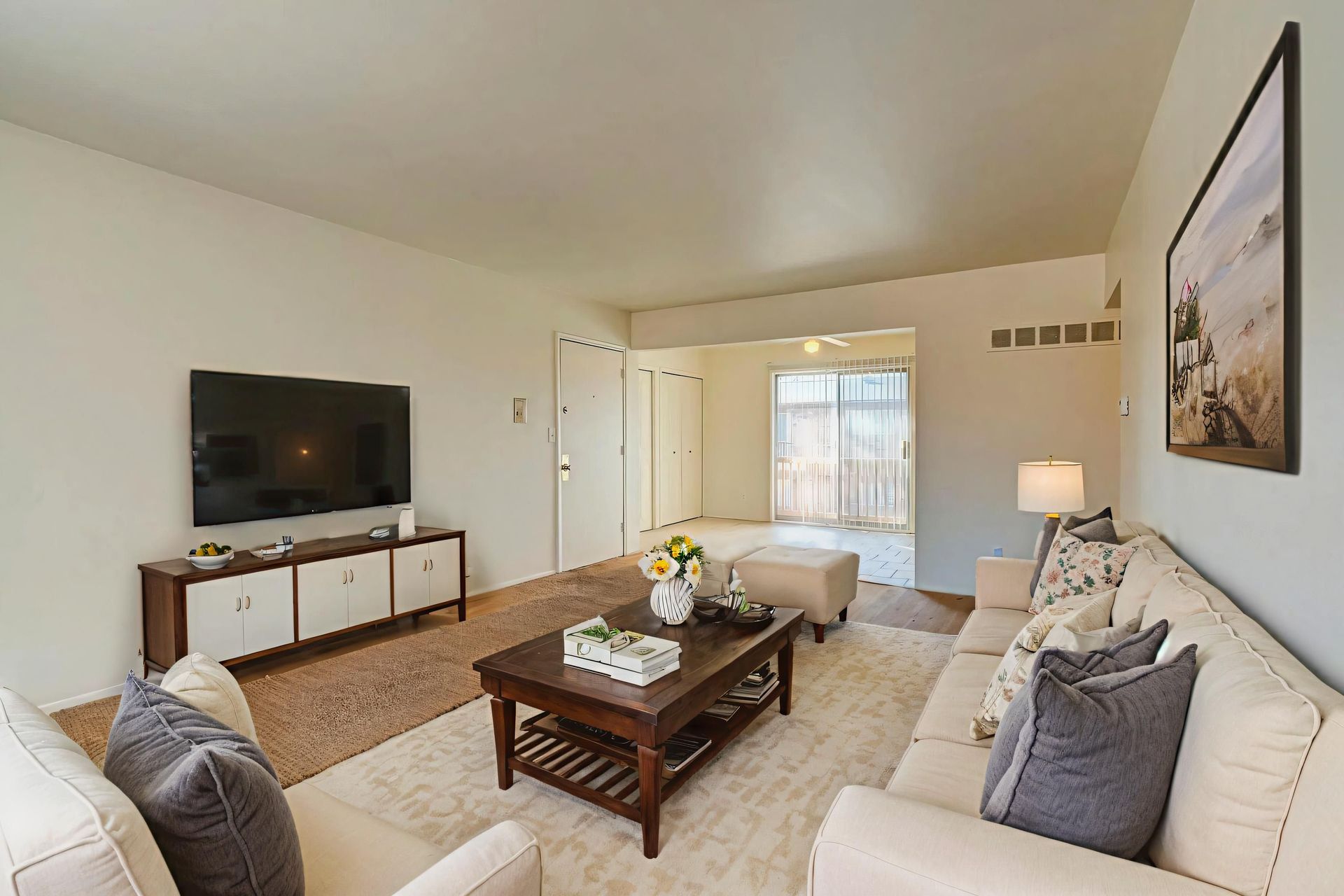 A living room with a ceiling fan and a kitchen