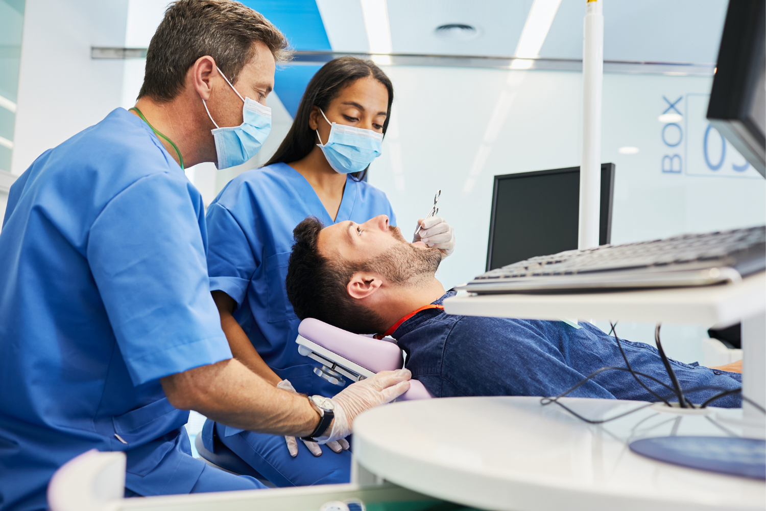 Person's mouth open during a dental exam. Dentist uses mirror and probe to examine the mouth.