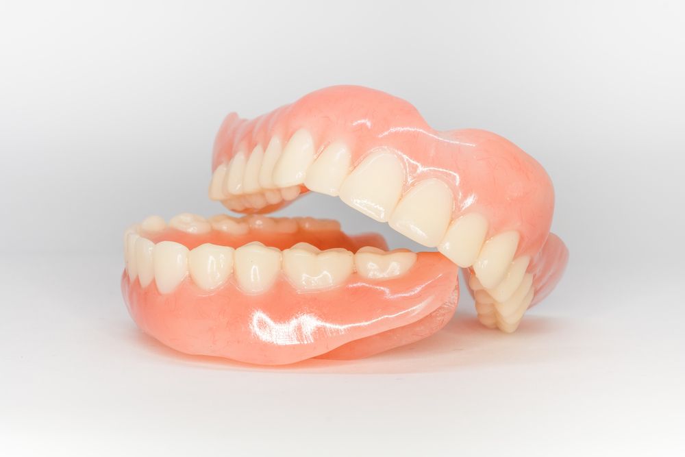 Person holding dentures, mouth open, about to place them in.