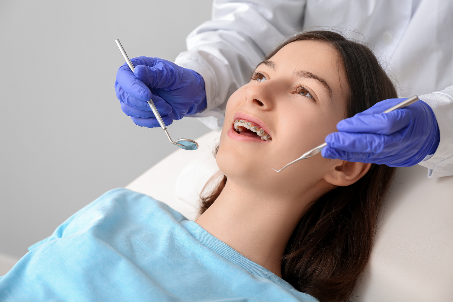 Person with braces getting dental exam. Dentist using tools in their mouth.