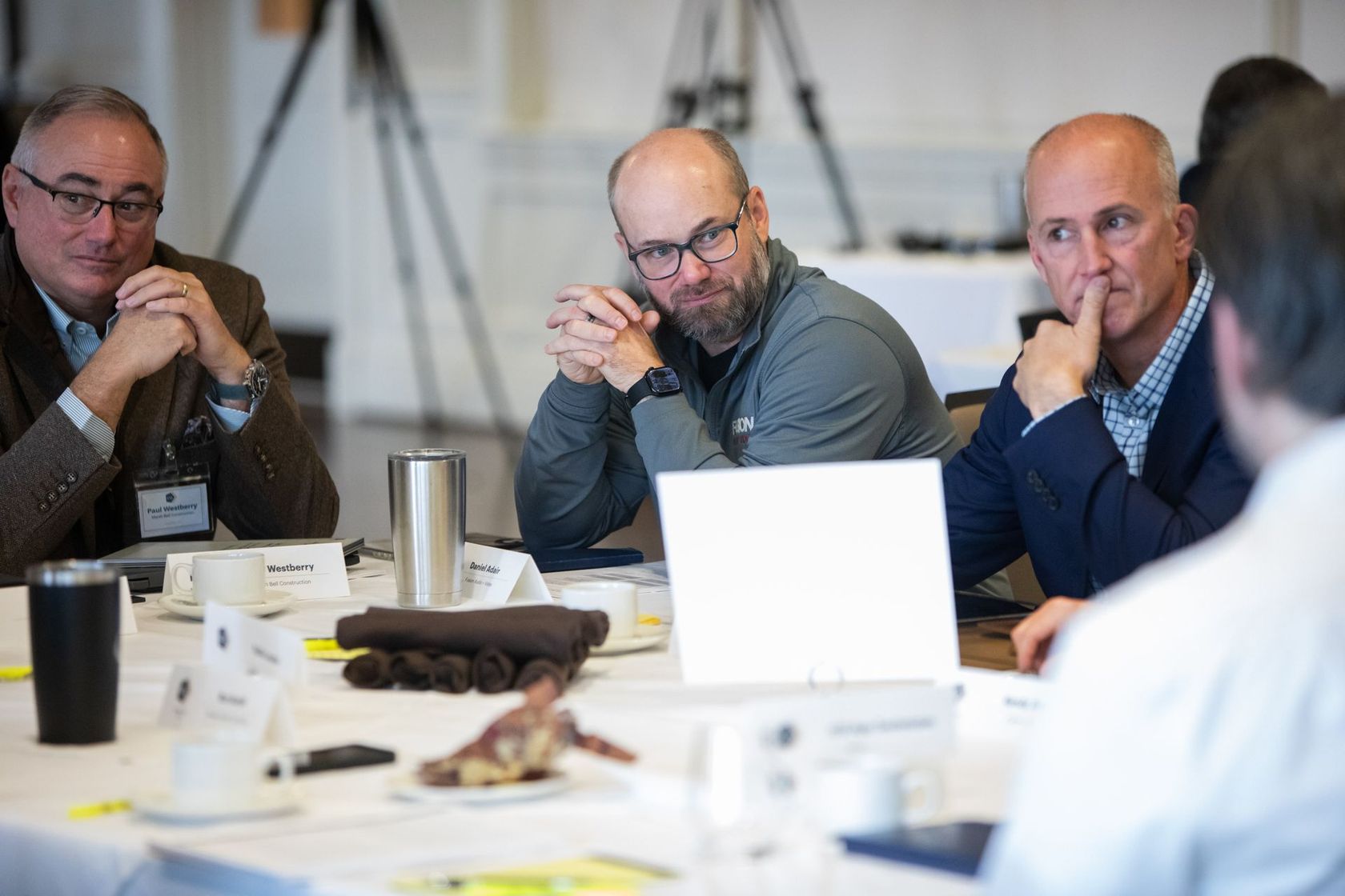 People seated around a conference table in a meeting, listening attentively.