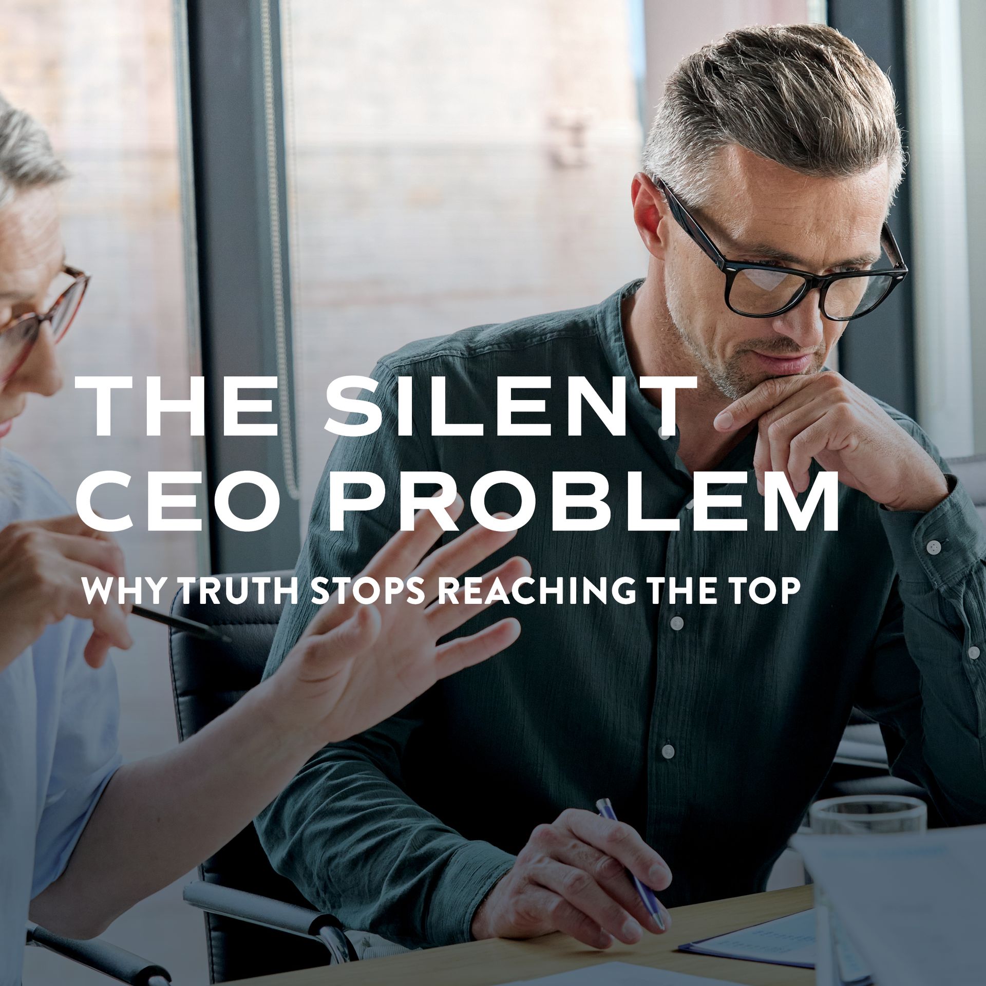Two business people at a table, one points, the other looks down thoughtfully. Text overlay: