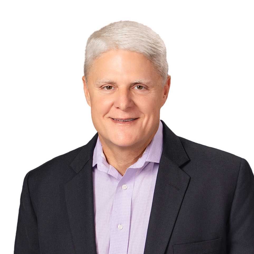 Studio portrait of a smiling person in a dark blazer and light purple shirt on a white background