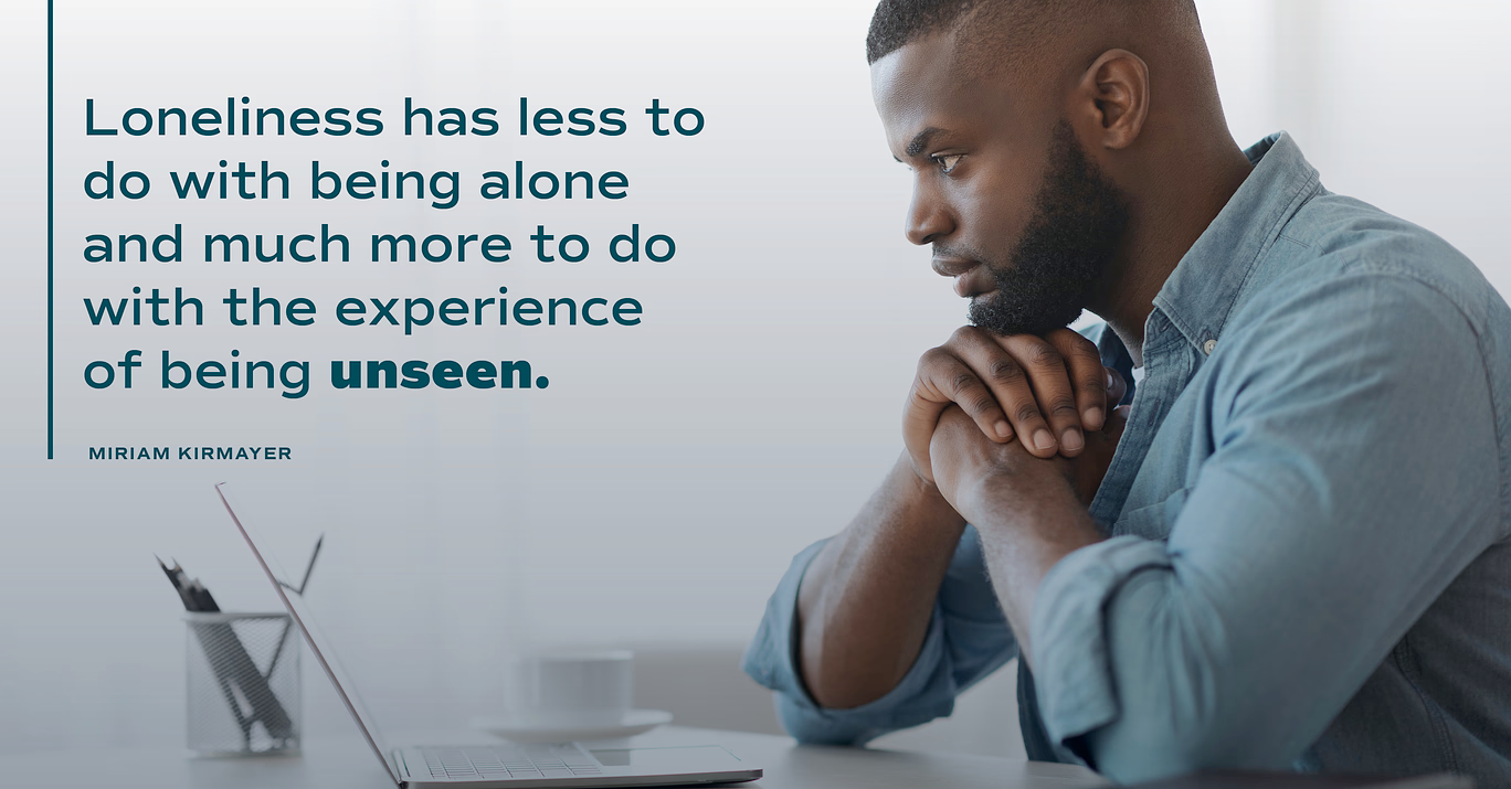 A man is sitting at a desk with a laptop and a quote about loneliness.