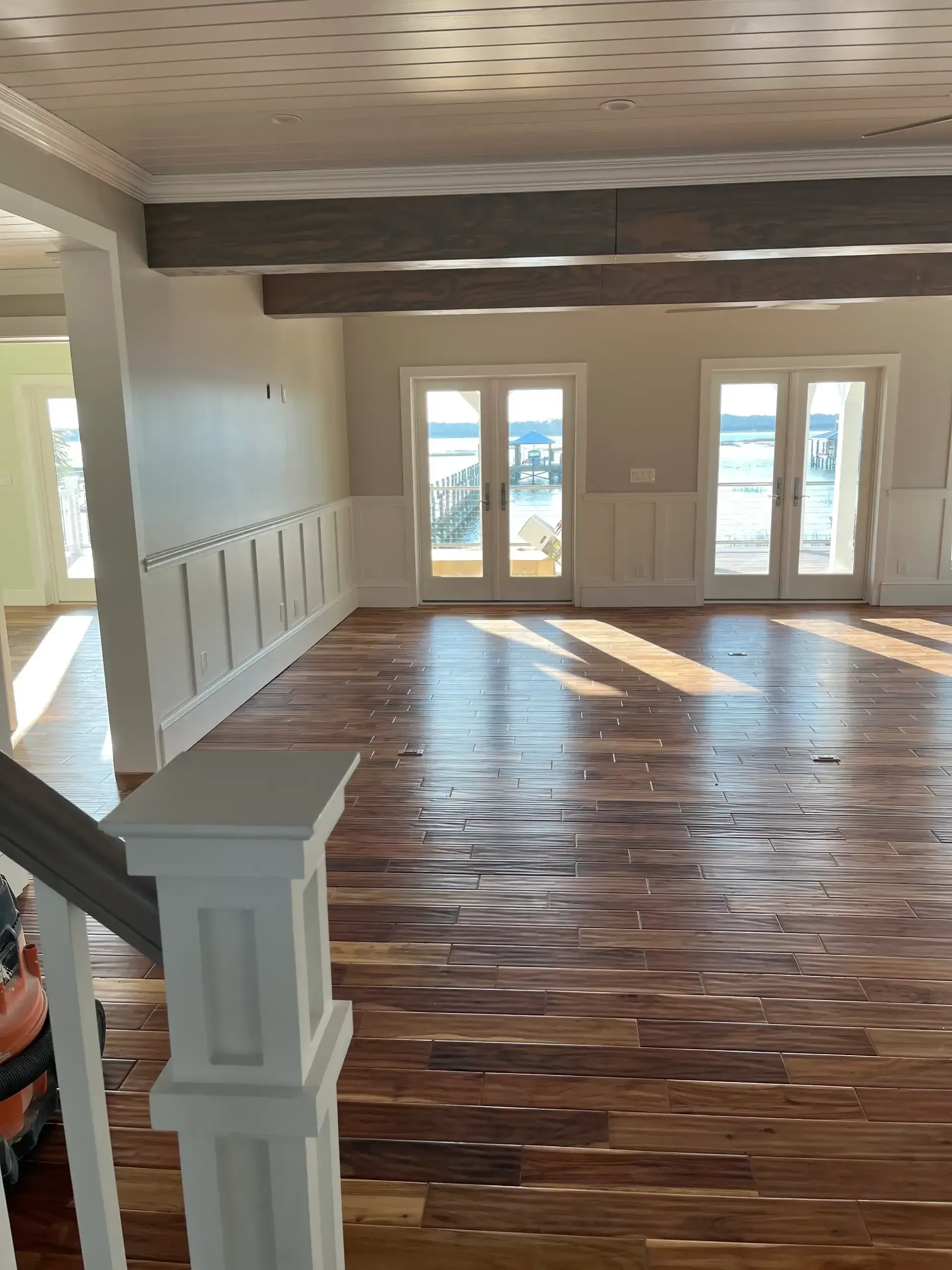 Exposed wood beam ceiling with French doors and wood flooring
