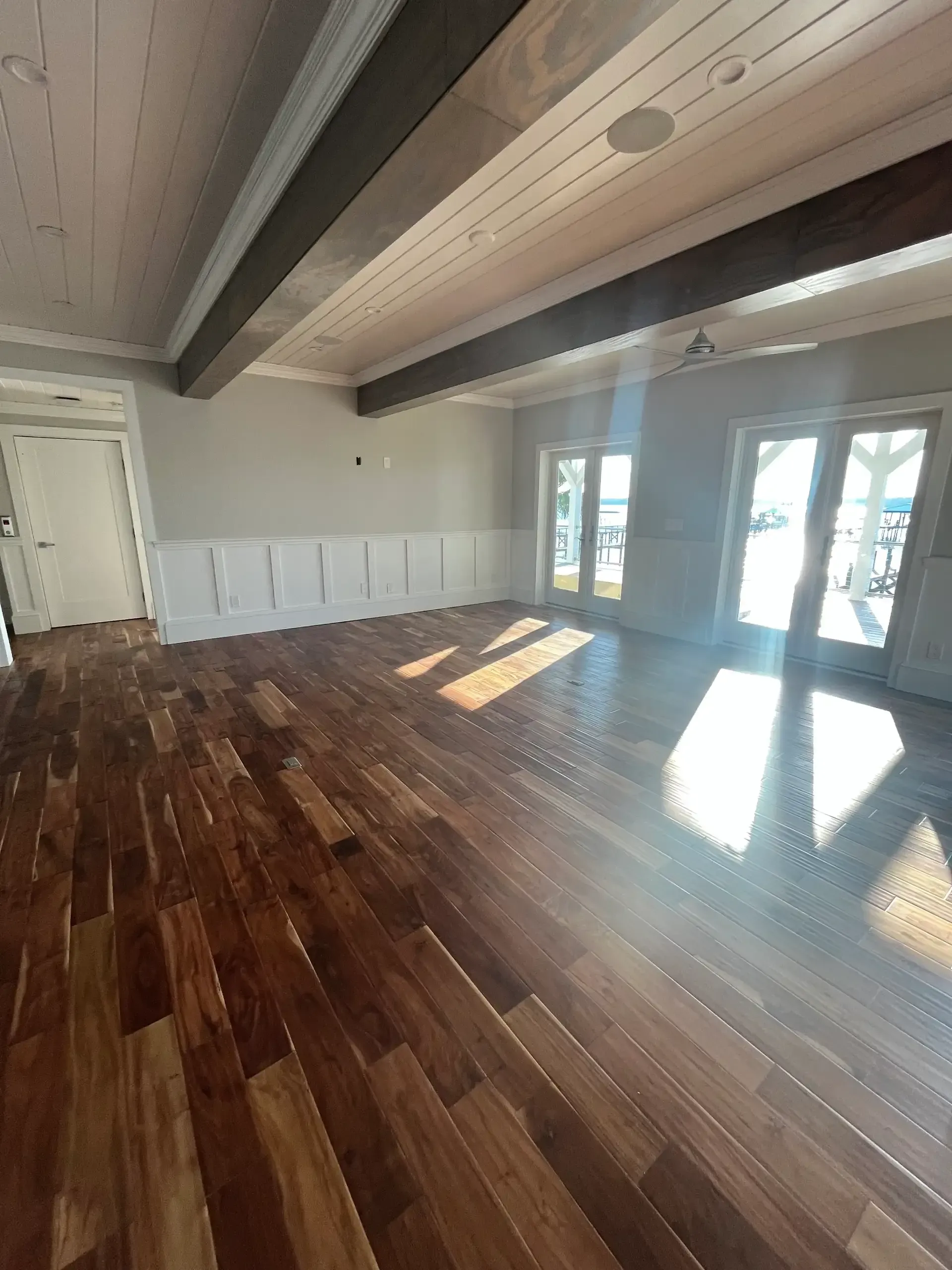 Exposed wood beams with French doors and hardwood flooring