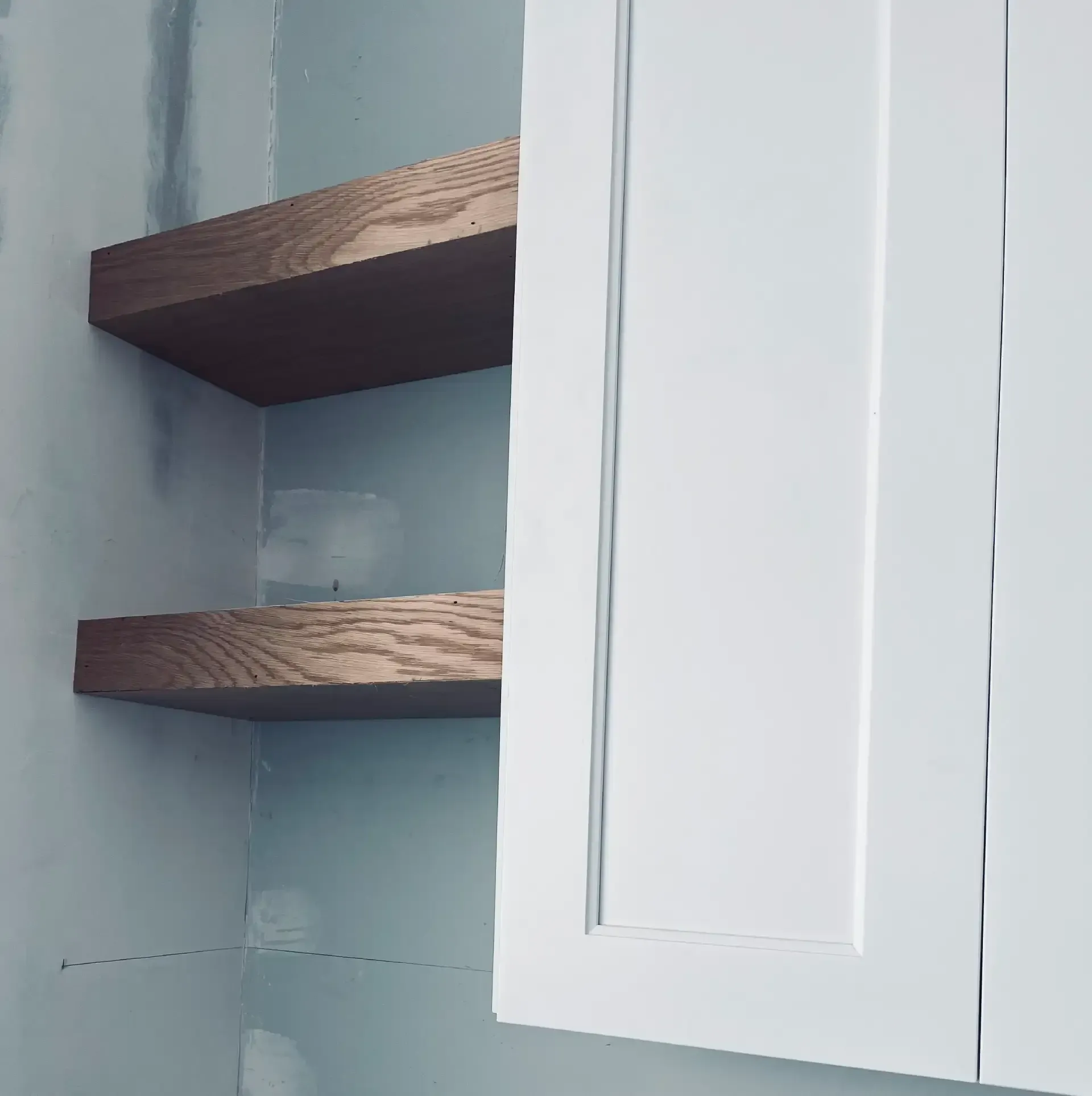 Wood floating shelves installed beside kitchen cabinet