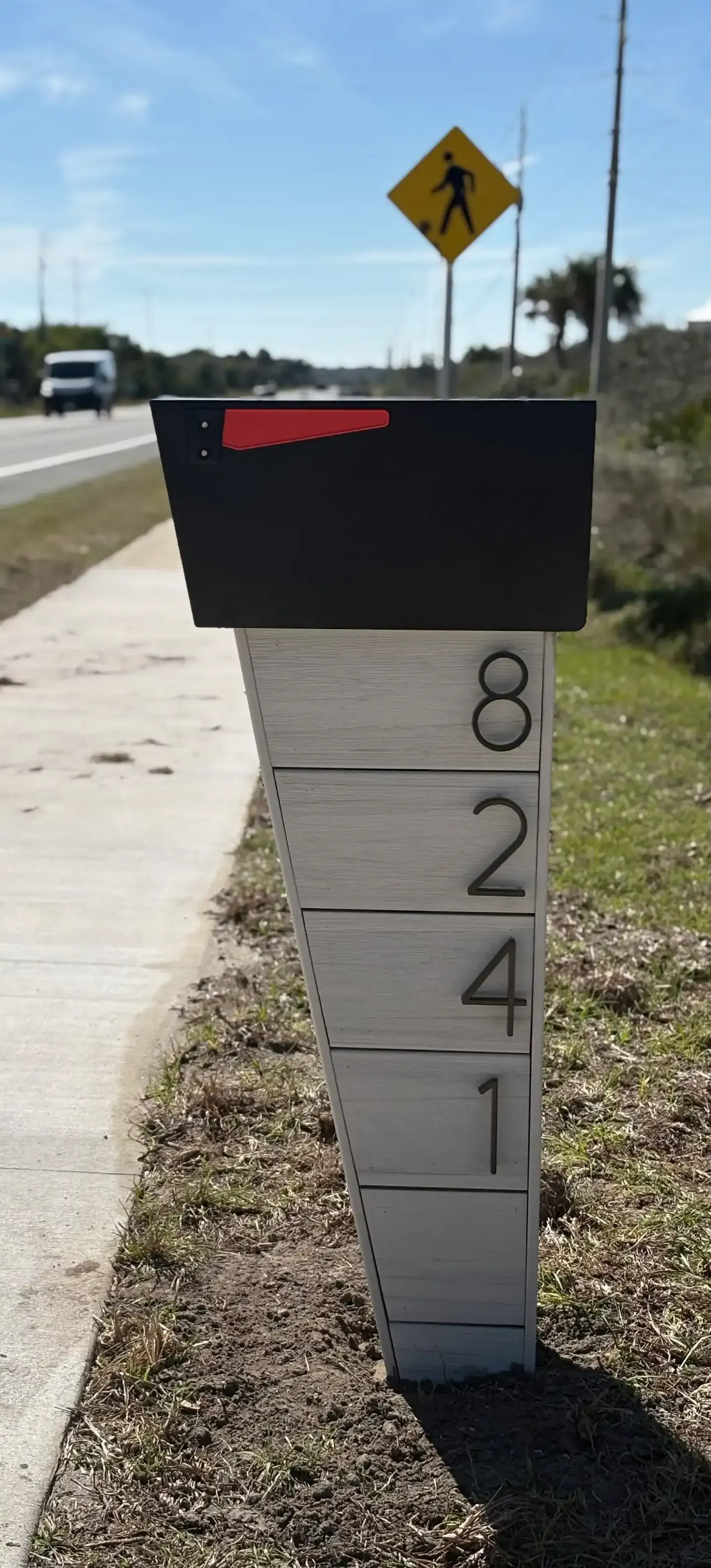 Modern custom mailbox with house numbers on wooden post