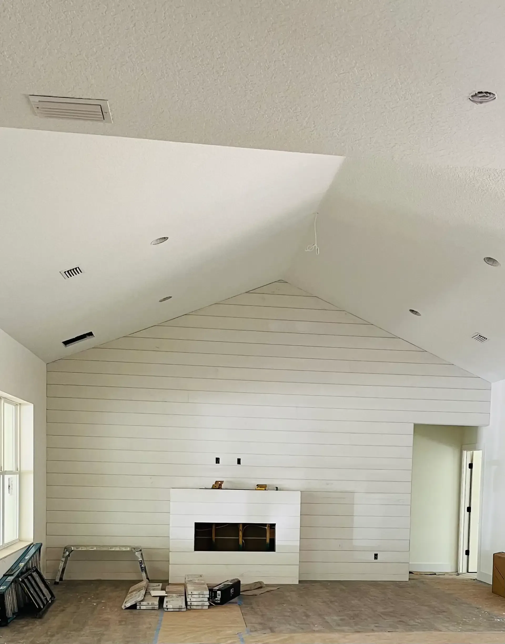 White shiplap accent wall with fireplace and vaulted ceiling