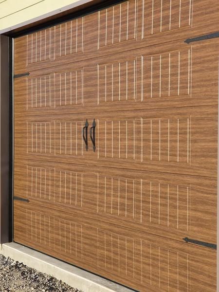 Wooden garage door with black handles and vertical white accents on a beige exterior wall
