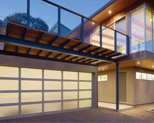 Modern two-story house exterior at dusk with glass balcony and illuminated garage door