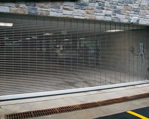 Closed metal security gate in front of a stone building entrance